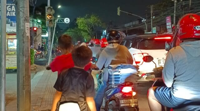 Dua orang anak menggunakan sepeda listrik di jalan raya ditengah padatnya kendaraan roda dua dan empat di jalan KH> Hasyim Ashari Kota Tangerang, Banten.